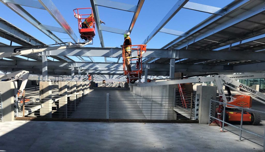 two workers in orange vests working at a construction site with steel beams
