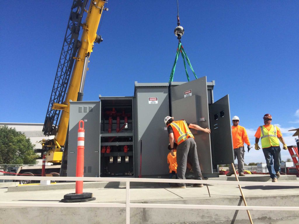 workers in orange vests inspecting an electrical panel