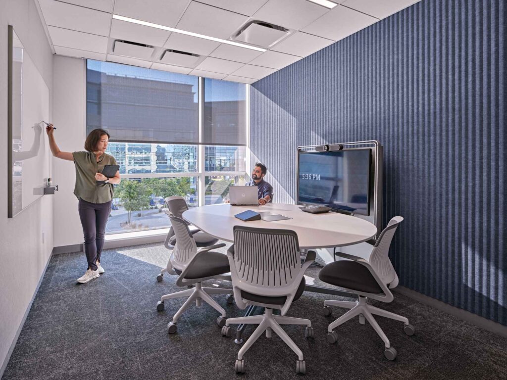 woman standing at white board while male colleague looks on
